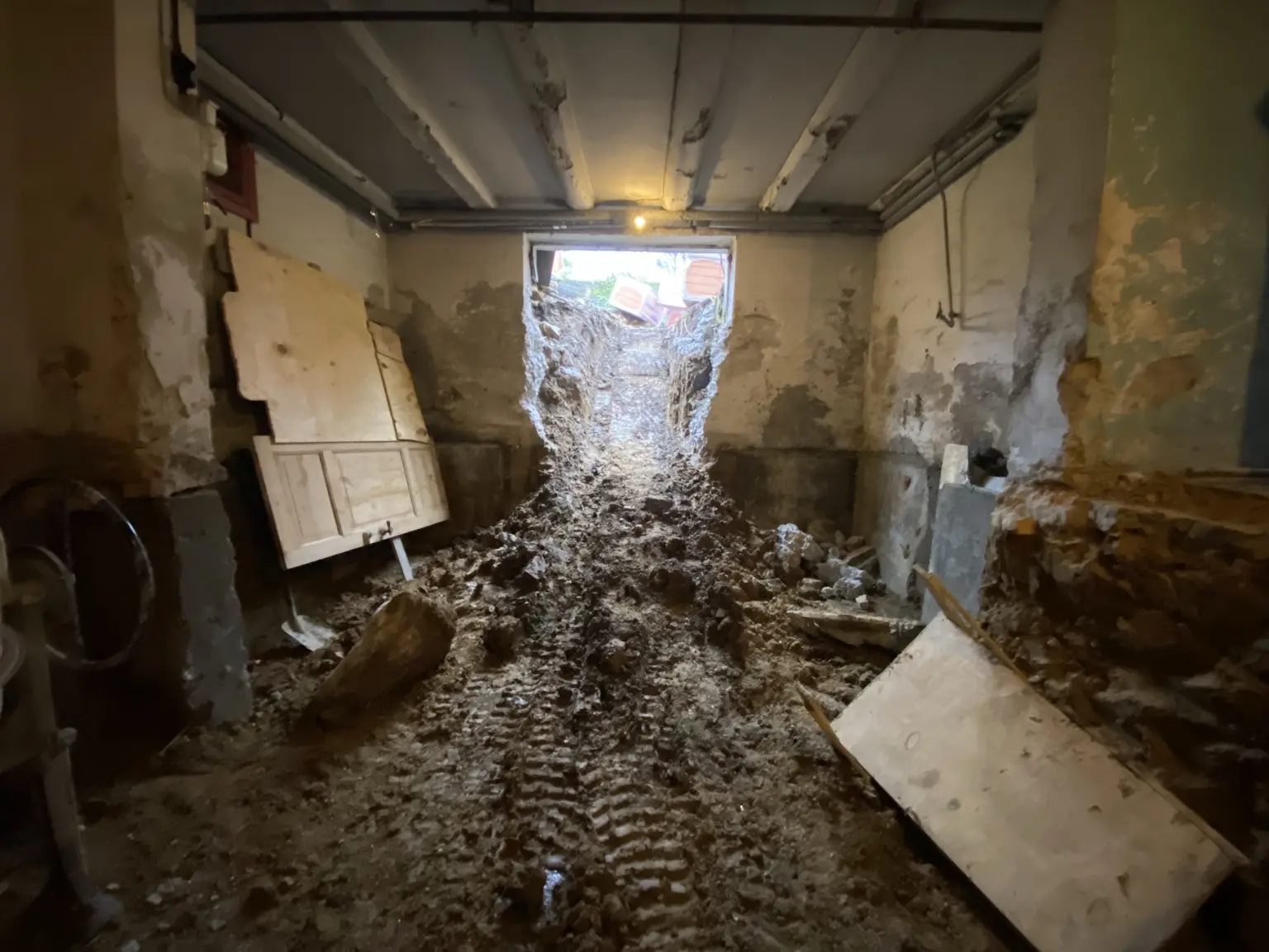 Udgravningsfasen med jord og opbrudte materialer i kælderen samt åbningen mod haven.